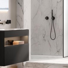 Ein modernes Badezimmer mit einem eleganten schwarzen Waschbecken und einem großen Spiegel, der das Licht reflektiert.