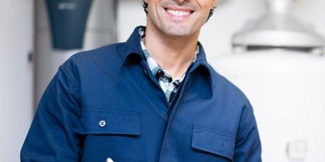 Ein Mann in Arbeitskleidung der ein Klemmbrett haelt