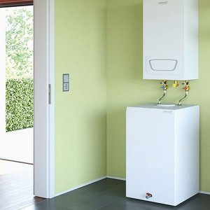 Moderne Waschküche mit grünen Wänden und Waschmaschine Ein heller Raum mit grünen Wänden, einer Waschmaschine und einem Wassertank, der an der Wand montiert ist.